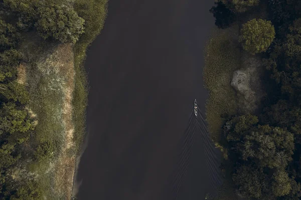 İnsanlarla dolu bir tekne tropikal ormandan geçiyor. Üst görünüm.