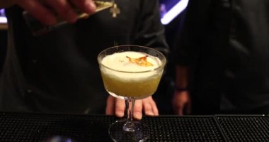 Barmen sarı bir kokteyl hazırlıyor..