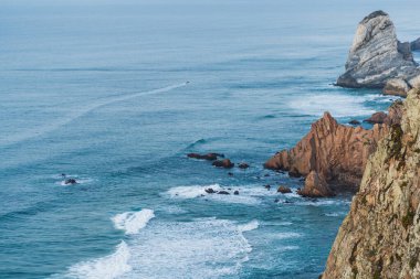 Mavi dalgalı kayalık sahil.