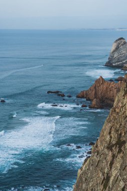 Mavi dalgalı kayalık sahil.