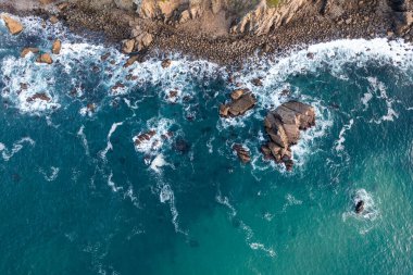 Mavi dalgalı kayalık sahil.