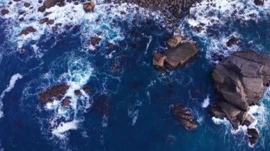 Okyanus dalgalarının kayalara çarpma görüntüsü.