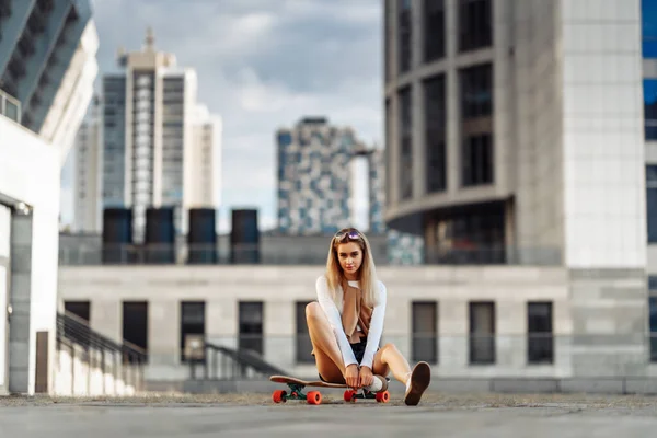 Sexy Mädchen sitzt auf einem Skateboard. — Stockfoto