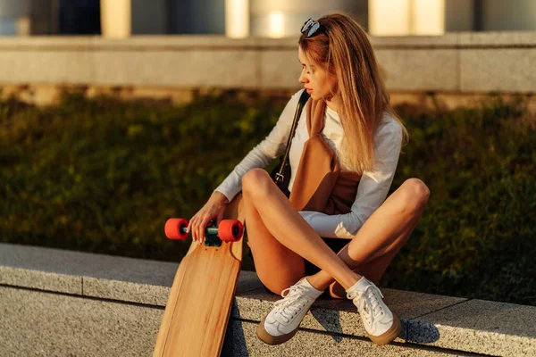 Piękna kobieta trzymająca longboard w rękach. Styl życia w mieście. — Zdjęcie stockowe