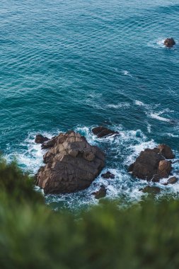 Mavi dalgalı kayalık sahil.