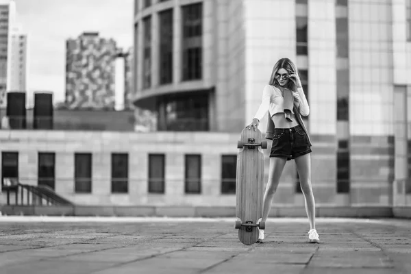 Una donna su uno skateboard in citta '. Bella foto in bianco e nero a contrasto di una donna in giro per la città. — Foto Stock