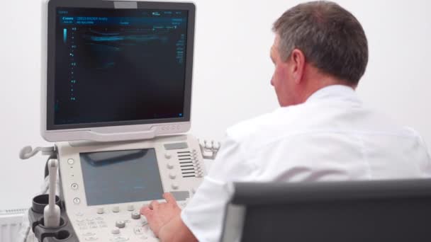 The doctor gives the woman an ultrasound of the thyroid gland. — Stockvideo