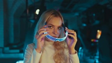 The blond puts on neon glasses. Cyber game. High quality 4k footage