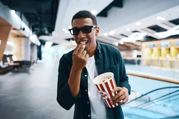 Cheerful man in 3D glasses with popcorn in his hands. Going to the cinema. High quality photo