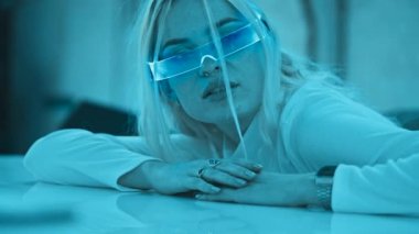 Cute blonde in futuristic fashion style. Neon glasses for a young woman. High quality 4k footage