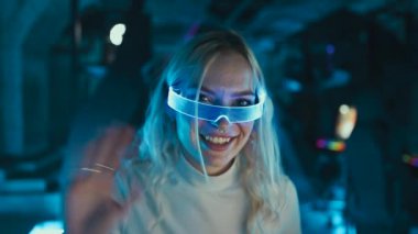 Cyber player welcomes the team.Blonde blogger in neon glasses. High quality 4k footage
