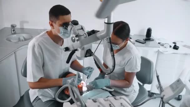 Zubař Léčí Pacienta Zuby Práce Zubní Klinice Mikroskopem Vysoce Kvalitní — Stock video