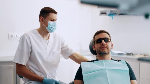 その男は歯医者と約束をした 医者は手術のための翼を下げる — ストック動画
