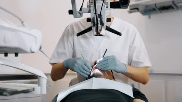 Dentysta Leczy Zęby Pacjentów Praca Klinice Dentystycznej Mikroskopem Wysokiej Jakości — Wideo stockowe