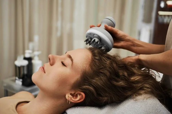 The master massages the womans head using a gadget. High quality photo
