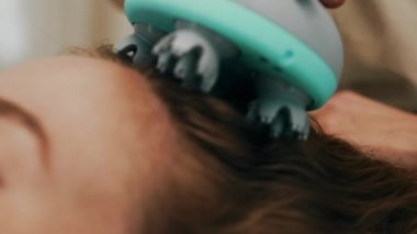 Bir kadın bir aletle kafa masajı yaptırıyor. Yüksek kalite 4k görüntü