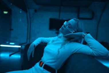 Neon mavi ışık fütüristik cam gözlük takan genç bir kadının üzerine düşüyor. Yüksek kalite fotoğraf