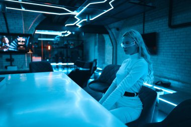 Neon mavi ışık fütüristik cam gözlük takan genç bir kadının üzerine düşüyor. Yüksek kalite fotoğraf