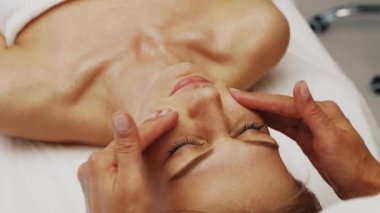 Usta profesyonel olarak genç bir kadının yüzüne masaj yapıyor. Yüksek kalite 4k görüntü