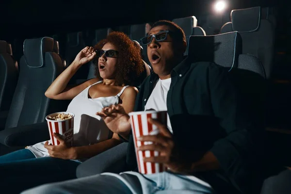 A couple in love, friends watching a movie with popcorn in the cinema. High quality photo