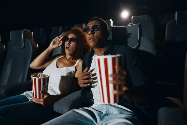 A couple in love, friends watching a movie with popcorn in the cinema. High quality photo