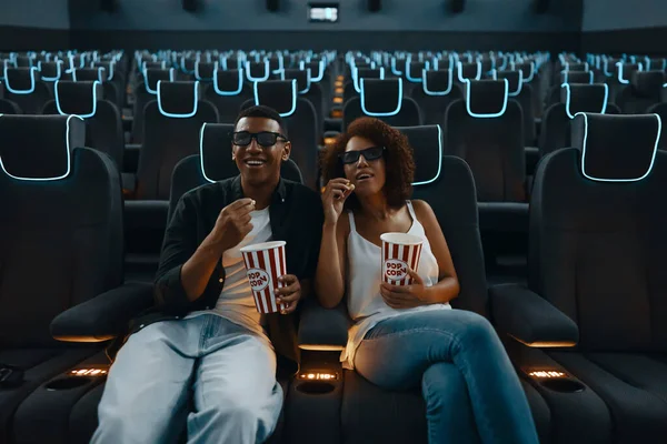 A couple with popcorn in an empty cinema watching a movie. High quality photo