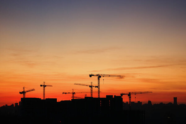Silhouette of construction cranes at sunset. High quality photo