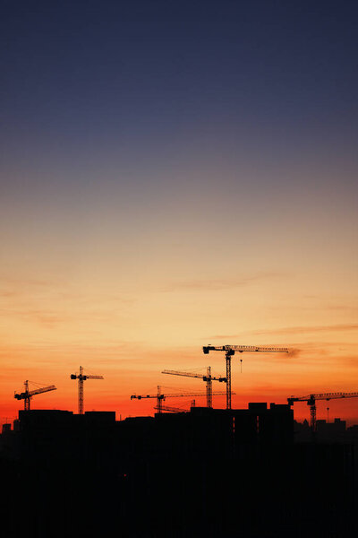 Silhouette of construction cranes at sunset. High quality photo