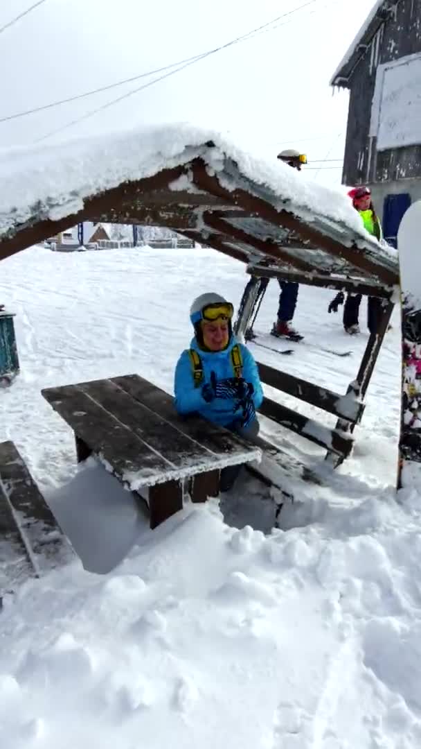 Женщина-лыжник позирует, сидя возле покрытого снегом стола — стоковое видео
