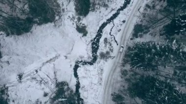 Tepedeki manzaralı araba dağların ormanlık alanındaki karlı patikadan geçiyor.