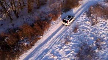 Kar tarlasında hareket eden SUV aracının hava görüntüsü