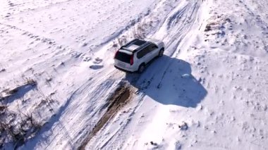 Kar tarlasında hareket eden SUV aracının hava görüntüsü