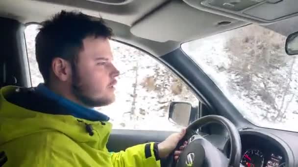 Человек за рулем автомобиля по шаткой снежной дороге в горах — стоковое видео