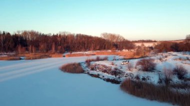 Göl kıyısında donmuş suyla duran bir SUV 'un hava görüntüsü.