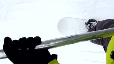 Snowboard 'cu yamacın tepesine çıkmak için kalkış asansörü kullanıyor.