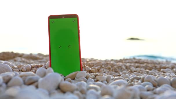 Telefon se zelenou obrazovkou na skalnaté pláži — Stock video