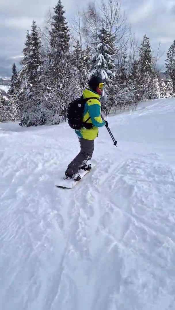Man snowboarder rijden door besneeuwde helling in prachtige bergen — Stockvideo