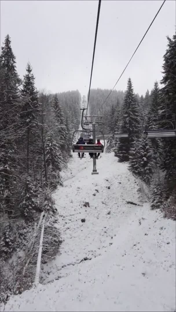 Bukovel, Oekraïne, 13 januari 2021: met de stoeltjeslift naar het skigebied als het sneeuwt — Stockvideo