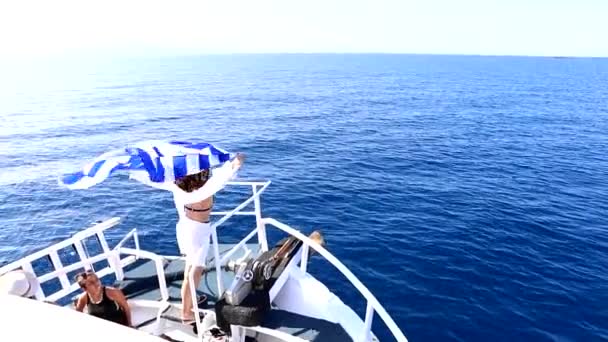 Lefkada, Řecko - 04. září 2021: žena držící řeckou vlajkovou plachtu se na lodi ohýbá kolem levého ostrova — Stock video