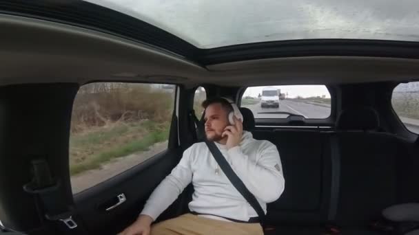Hombre sentado en el coche trasero se sienta mirando en la ventana — Vídeos de Stock