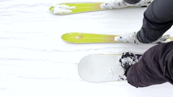Snowboardåkare med skidåkare som använder draglift för att få toppen av backen — Stockvideo