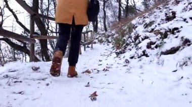 Kadın bacakları kışın botlarla kapanır. Karlı patikaların yanından yürür.