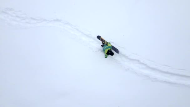 Homme grimpant par une colline enneigée avec snowboard — Video