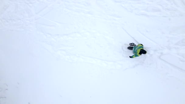 Man klimmen door besneeuwde heuvel met snowboard — Stockvideo