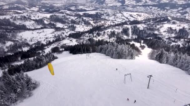 Skidåkare skärmflygning ovanför skidorten — Stockvideo