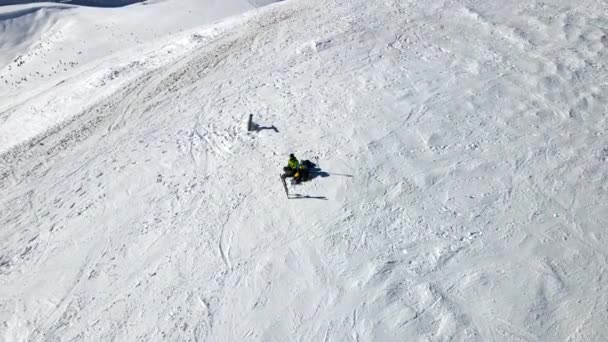 Par skidåkare och snowboardåkare har kul på toppen av kullen på solig dag — Stockvideo