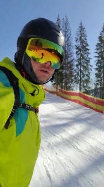 Snowboard sporcusu yamaçtan inerken selfie çekiyor.