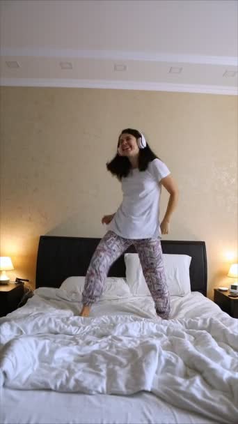 Wanita menari di tempat tidur mendengarkan musik dengan headset — Stok Video
