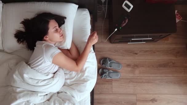 Mujer despertando tomando el teléfono de la mesa de noche — Vídeos de Stock