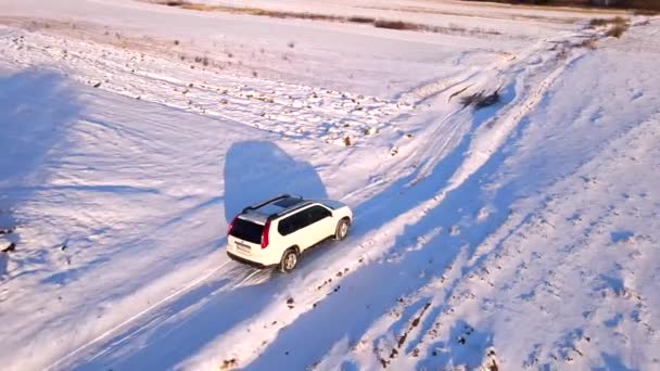 Повітряний вид на автомобіль на сніговій польовій дорозі — стокове відео